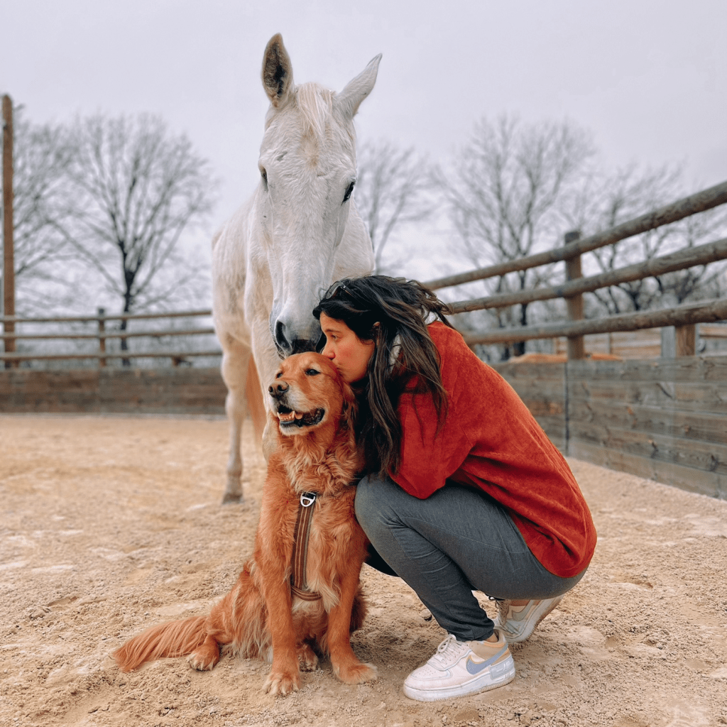 Photo de Salomé avec ses animaux, qui embrasse son chien golden avec derrière son cheval blanc